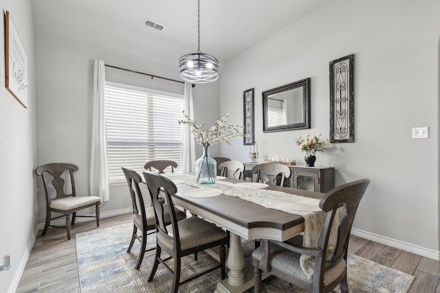 dining space featuring baseboards, visible vents, and light wood finished floors