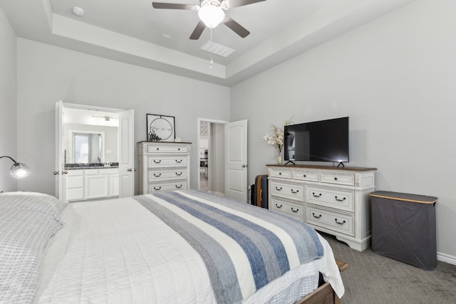 bedroom featuring ensuite bath, a ceiling fan, a raised ceiling, and carpet flooring