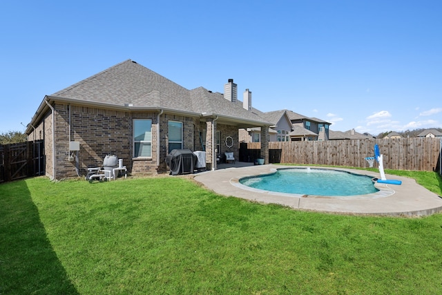 rear view of property with a yard, brick siding, and a fenced backyard