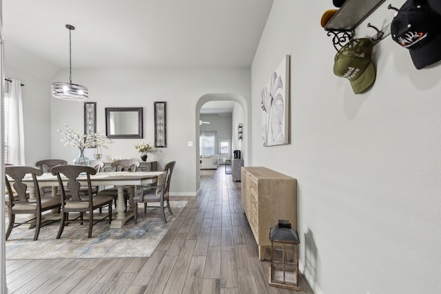 dining room with arched walkways, baseboards, and wood finished floors