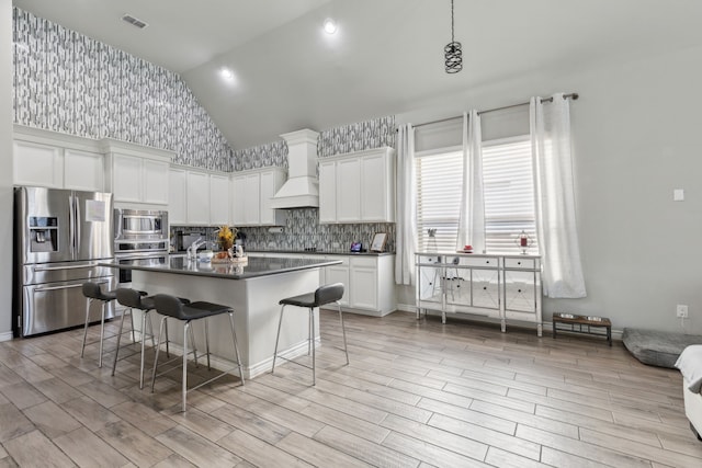 kitchen with dark countertops, visible vents, appliances with stainless steel finishes, white cabinetry, and a kitchen bar