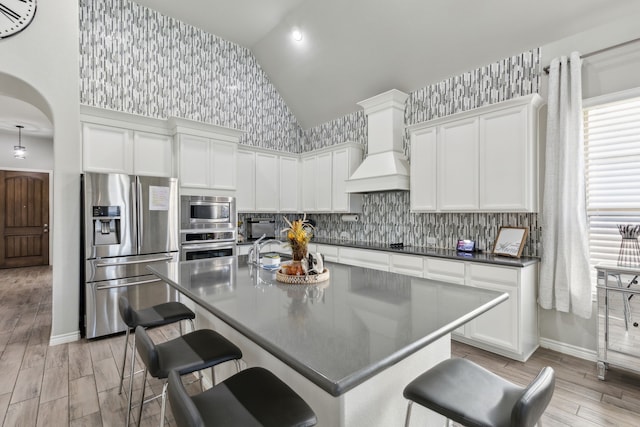 kitchen featuring stainless steel appliances, a breakfast bar area, white cabinets, and custom exhaust hood