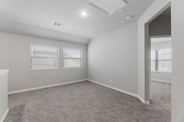 unfurnished room featuring lofted ceiling, carpet floors, visible vents, and baseboards