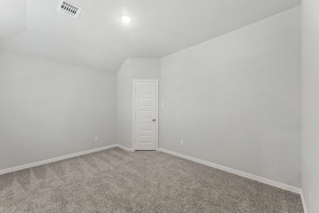 unfurnished room with carpet, visible vents, vaulted ceiling, and baseboards