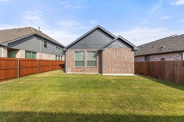 back of property with brick siding, a lawn, and a fenced backyard