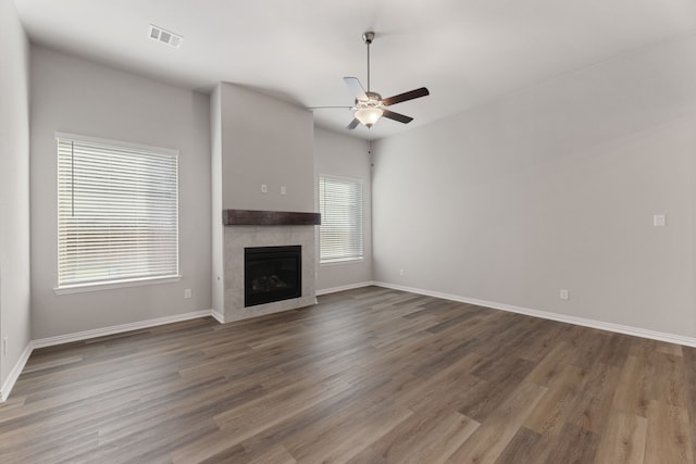 unfurnished living room featuring a tile fireplace, ceiling fan, baseboards, and wood finished floors