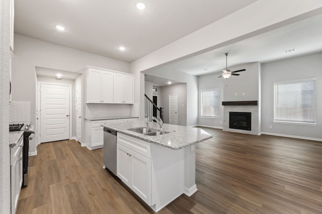 kitchen featuring a sink, range with gas stovetop, stainless steel dishwasher, dark wood-style floors, and a glass covered fireplace