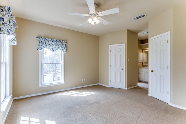 unfurnished bedroom featuring visible vents, light carpet, baseboards, and ceiling fan