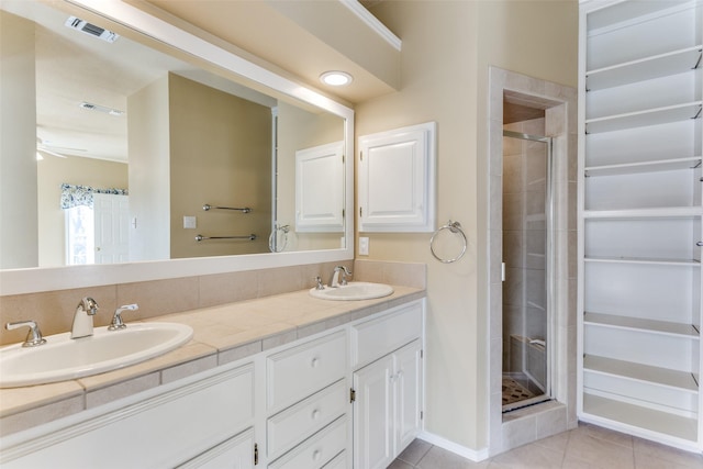 bathroom featuring tile patterned flooring, visible vents, a stall shower, and a sink