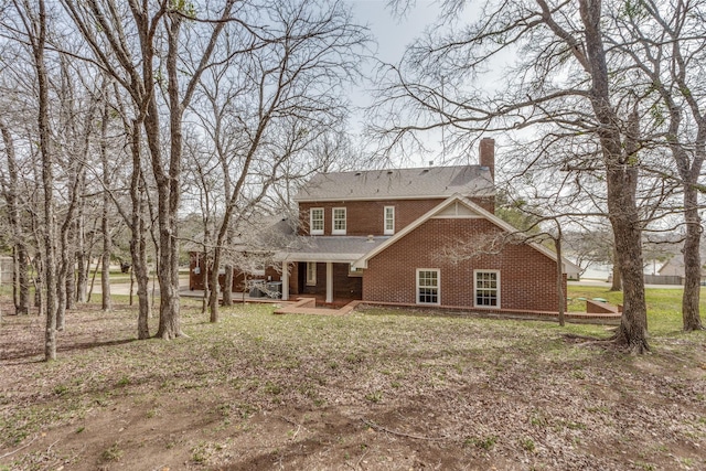 back of property featuring brick siding and a chimney