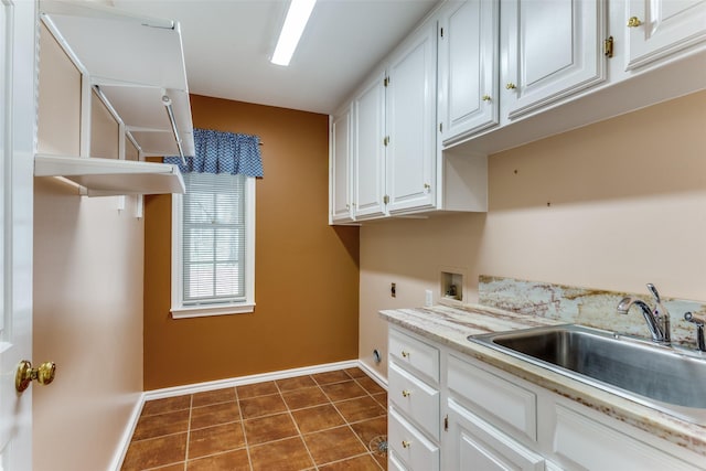 washroom with baseboards, dark tile patterned floors, washer hookup, cabinet space, and a sink