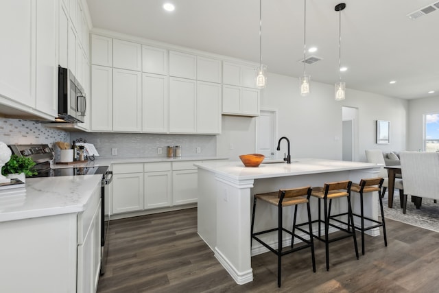 kitchen with stainless steel appliances, backsplash, visible vents, and white cabinetry