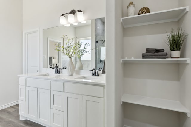 full bathroom with a shower, wood finished floors, a sink, and double vanity