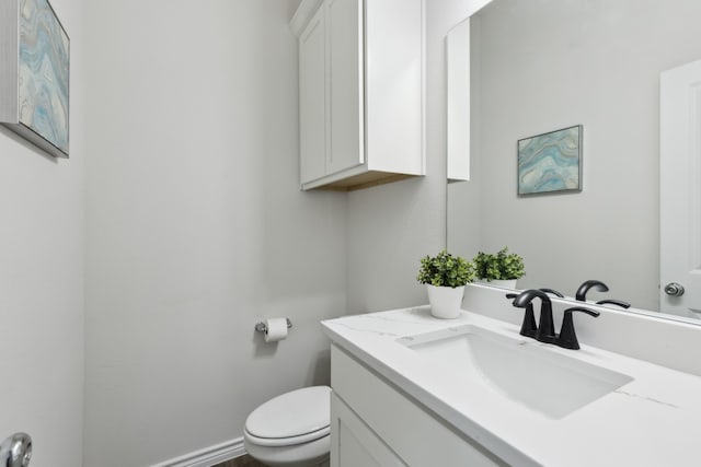 bathroom featuring baseboards, vanity, and toilet