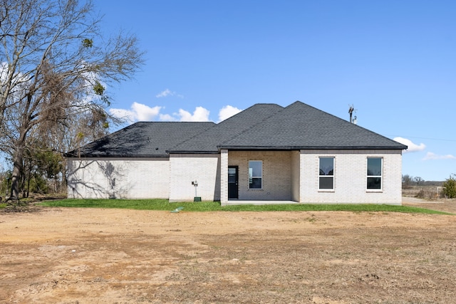 back of property with roof with shingles and brick siding