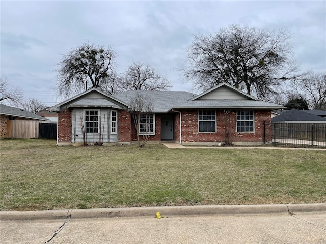 view of front facade featuring fence, a front lawn, and brick siding