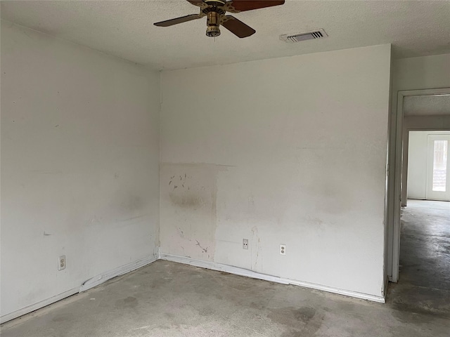 spare room with a ceiling fan, concrete floors, visible vents, and a textured ceiling