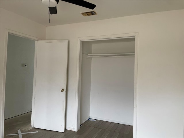 unfurnished bedroom with ceiling fan, visible vents, a closet, and wood finished floors