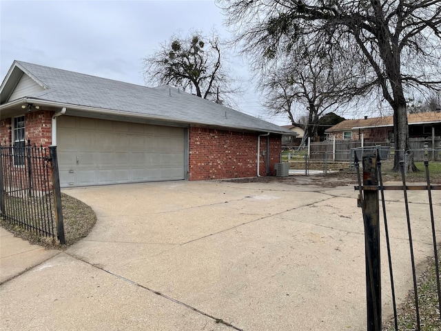 view of side of property with a garage, concrete driveway, fence, cooling unit, and brick siding