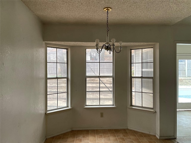 unfurnished dining area with a textured ceiling, baseboards, a wealth of natural light, and a notable chandelier