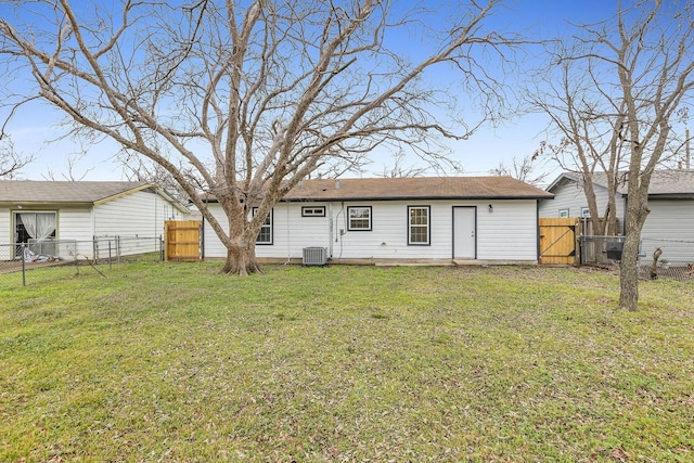 rear view of property with central AC unit, a lawn, fence, and a gate