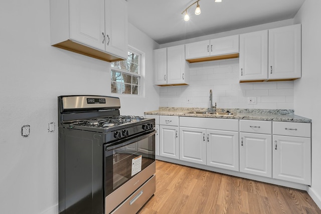 kitchen with white cabinets, a sink, light wood finished floors, and gas range