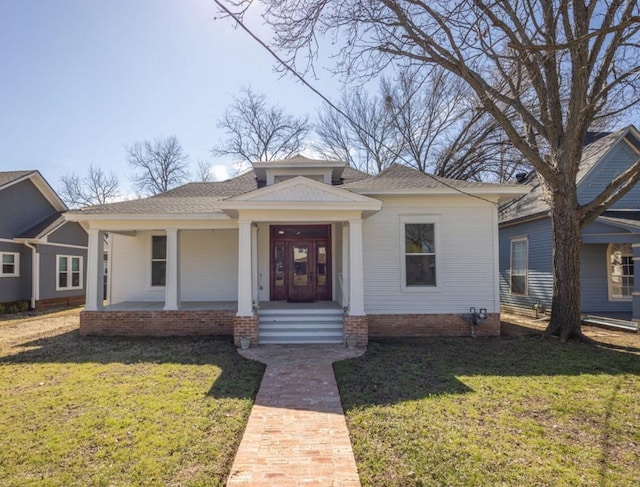 bungalow-style home featuring a front yard and roof with shingles