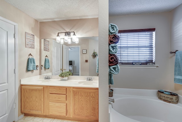 bathroom featuring a textured ceiling, double vanity, a sink, and a garden tub