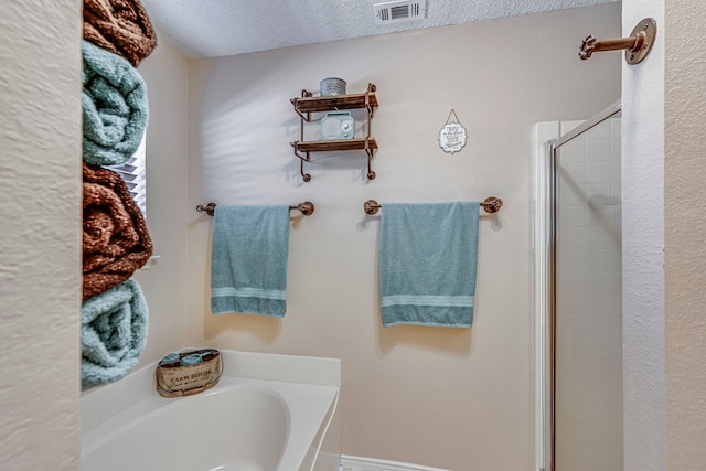 bathroom with a bath, a textured ceiling, a shower stall, and visible vents