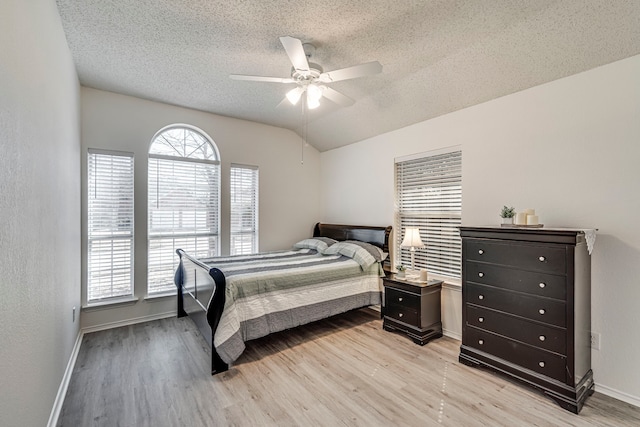 bedroom featuring light wood-type flooring, vaulted ceiling, a textured ceiling, and baseboards