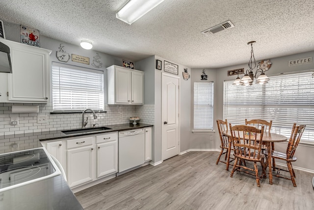 kitchen with white dishwasher, a sink, visible vents, white cabinetry, and light wood finished floors