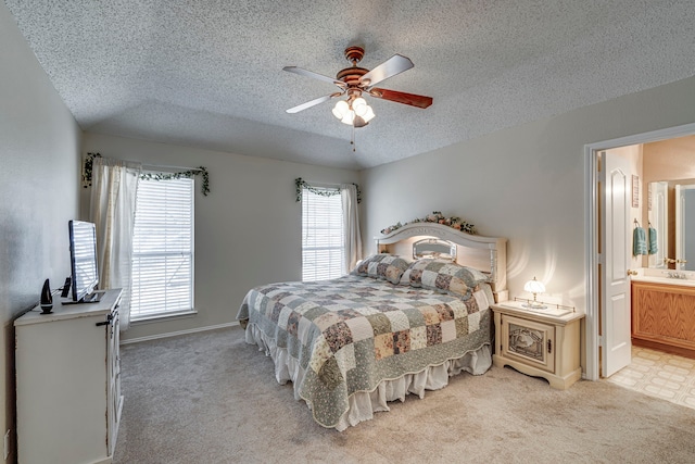 bedroom featuring ensuite bath, ceiling fan, a textured ceiling, and light colored carpet