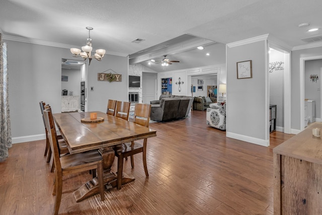 dining room with ceiling fan with notable chandelier, ornamental molding, visible vents, and hardwood / wood-style flooring