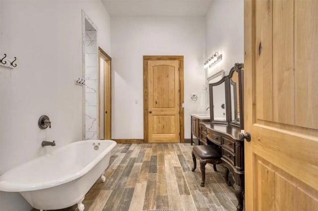 full bathroom featuring a freestanding tub, baseboards, wood finished floors, and vanity