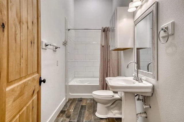 bathroom featuring shower / bath combination with curtain, wood finish floors, baseboards, and toilet