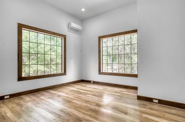 empty room featuring a wall mounted AC, recessed lighting, wood finished floors, and baseboards