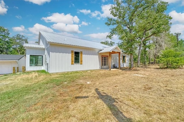 rear view of house with metal roof and a yard