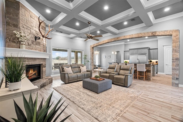 living area featuring a high ceiling, coffered ceiling, beamed ceiling, and a stone fireplace