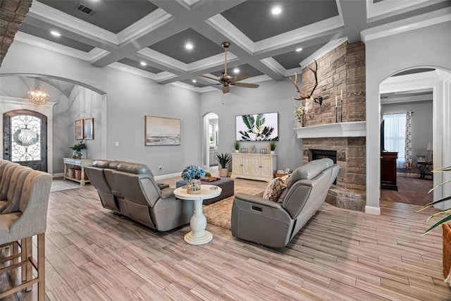 living room with light wood-type flooring, a fireplace, visible vents, and arched walkways