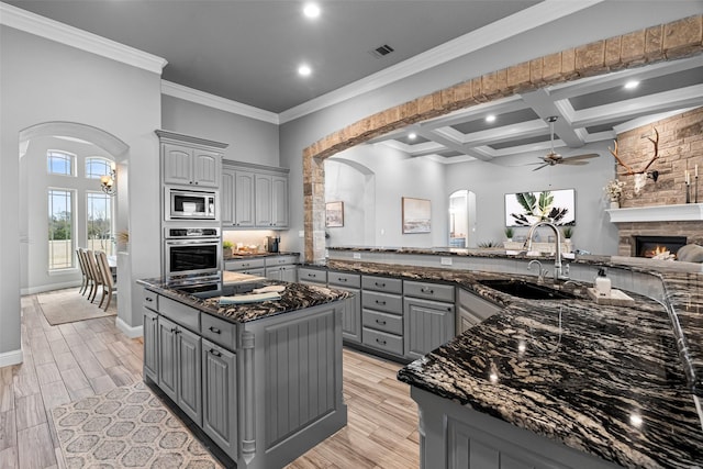 kitchen featuring arched walkways, appliances with stainless steel finishes, gray cabinets, and a sink