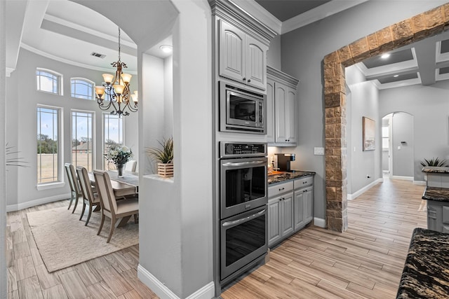 kitchen featuring arched walkways, gray cabinetry, stainless steel appliances, crown molding, and wood finish floors