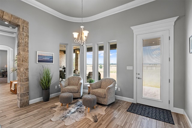 sitting room with baseboards, arched walkways, wood finished floors, crown molding, and a chandelier