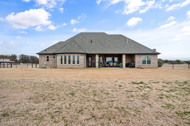 rear view of house with roof with shingles, fence, and a patio