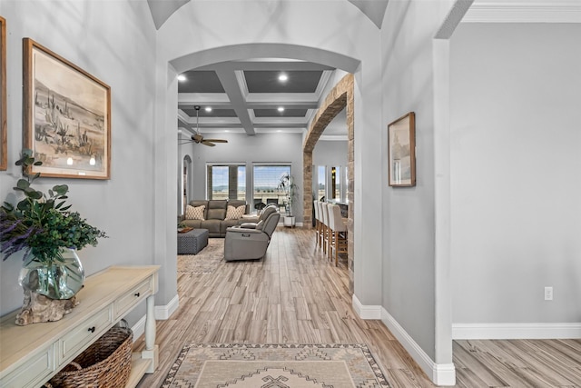 hall featuring light wood-style floors, arched walkways, coffered ceiling, and baseboards