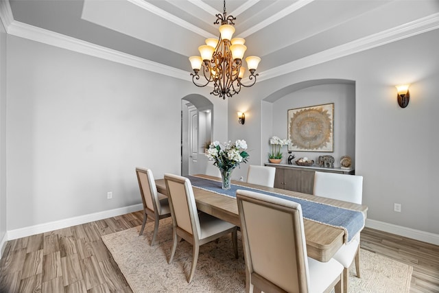 dining room featuring a chandelier, a tray ceiling, baseboards, and wood finished floors