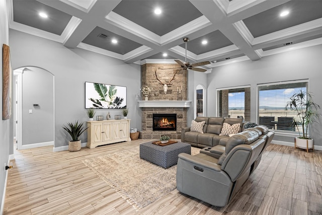 living area featuring light wood-type flooring, visible vents, a fireplace, and arched walkways