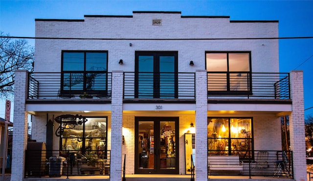 back of house featuring a balcony, french doors, and brick siding