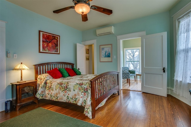 bedroom featuring a ceiling fan, an AC wall unit, and wood finished floors