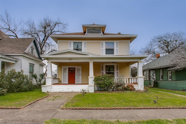 american foursquare style home featuring a porch and a front yard