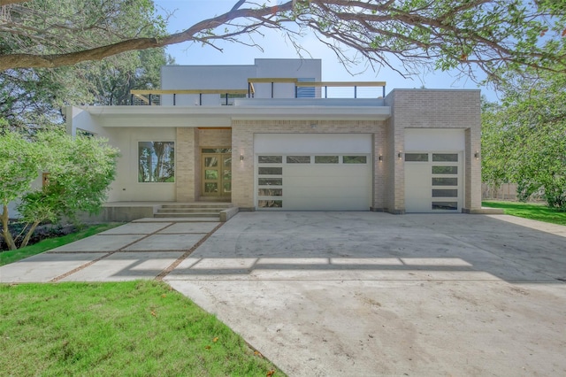 contemporary home featuring a garage, concrete driveway, brick siding, and stucco siding